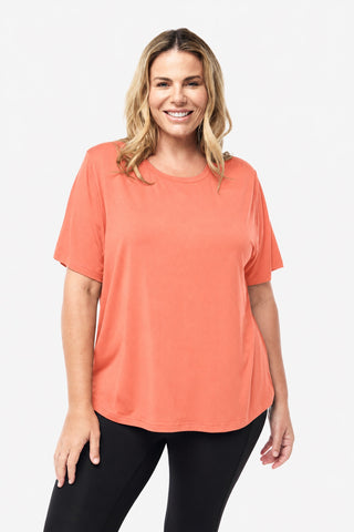 Classic Bamboo T-Shirt in Coral, front view on model smiling, styled with black leggings.
