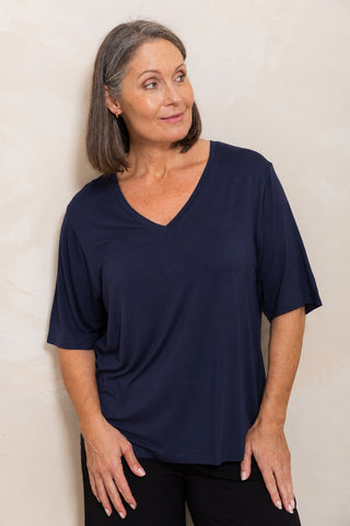 Bamboo V-Neck T-Shirt in Navy, front view on model leaning against a wall, styled with black pants.