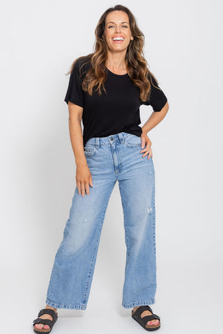 Classic Bamboo T-Shirt in Black, full length front view on model with hand on hip, styled with wide leg jeans and sandals.