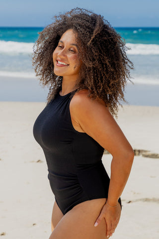 Coogee Core Support One Piece Swim in Black Texture, side view on model at the beach
