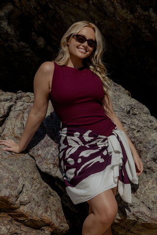 Coogee Core Support One Piece Swim in Dark Cherry Texture, front view on model styled with a sarong on the rocks