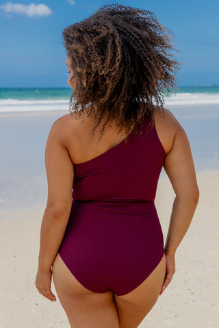 Esperance Core Support One Piece Swim in Dark Cherry Texture, back view on model at the beach