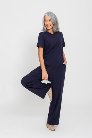 Motion Wide Leg Tailored Pant in Navy, model mid stretch with leg raised.