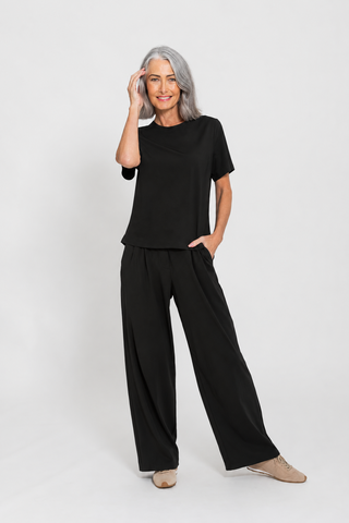Motion Tee in Black, full body front view on model styled with wide leg pants.
