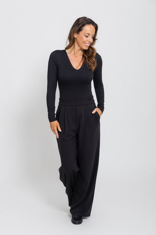 Sculpt V Neck Bodysuit in Black styled with wide leg trousers, studio full length.