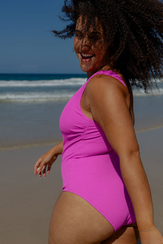 Sorrento Core Support One Piece Swim in Hot Pink Texture, side view on model at the beach