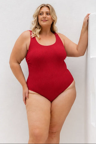Sorrento Core Support One Piece Swim in Red Texture, front view on model with hand on a white wall.