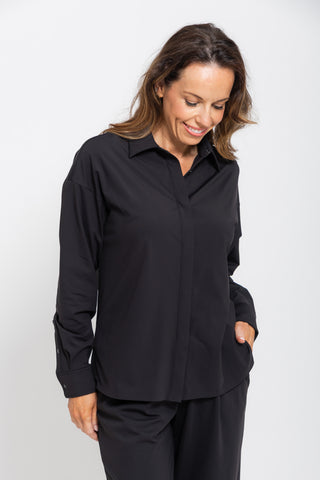 Motion Shirt in Black, close up front view on model smiling with hands in pockets.