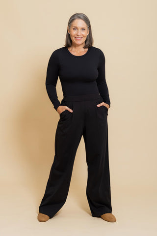 Sculpt Crew Neck Bodysuit in black worn with tailored pants, seated